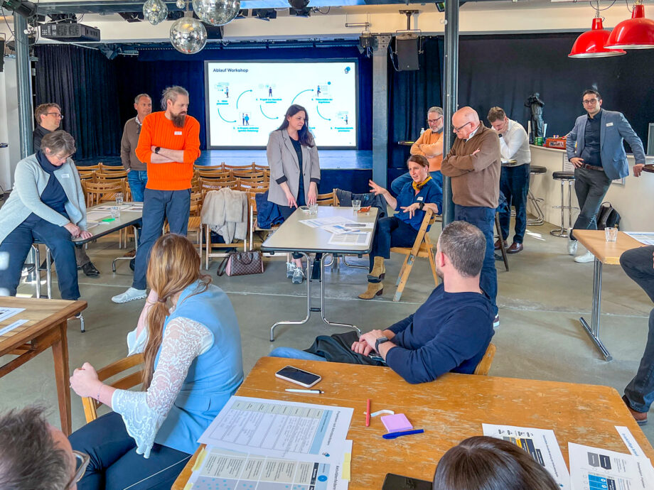 Dieses Bild zeigt ca. 15 Personen, die an einem Workshop miteinander diskutieren.