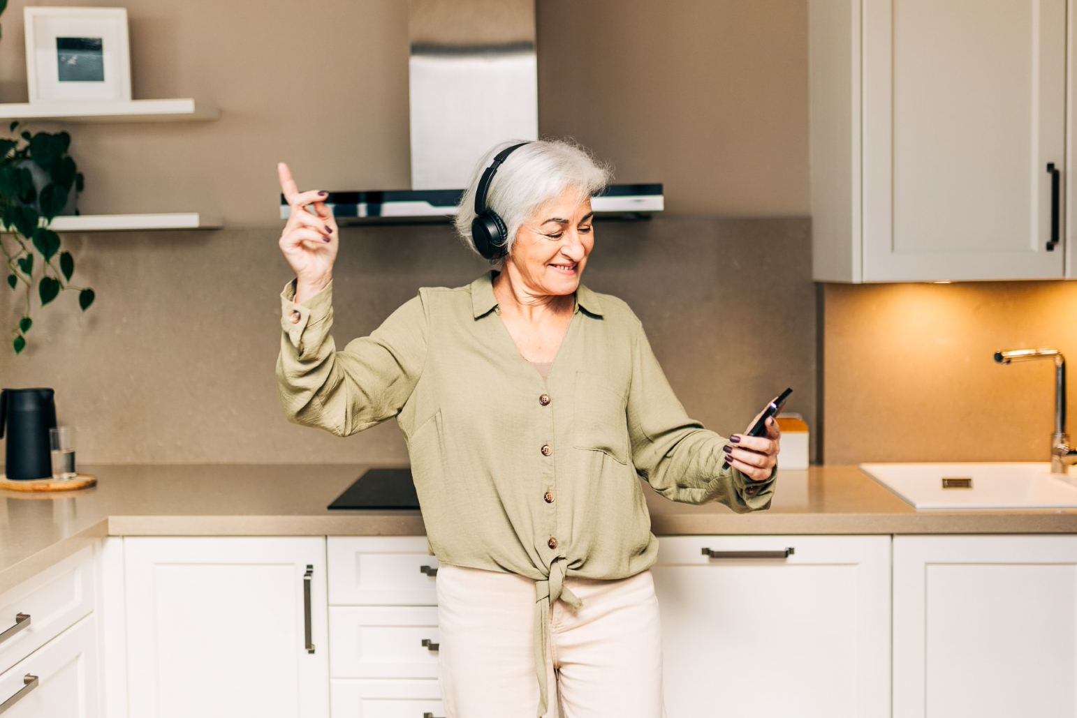Dieses Bild zeigt eine ältere Dame, die in ihrer Küche tanzt. Es steht symbolisch für verschieden Alterswohnmöglichkeiten von Bonacasa.
